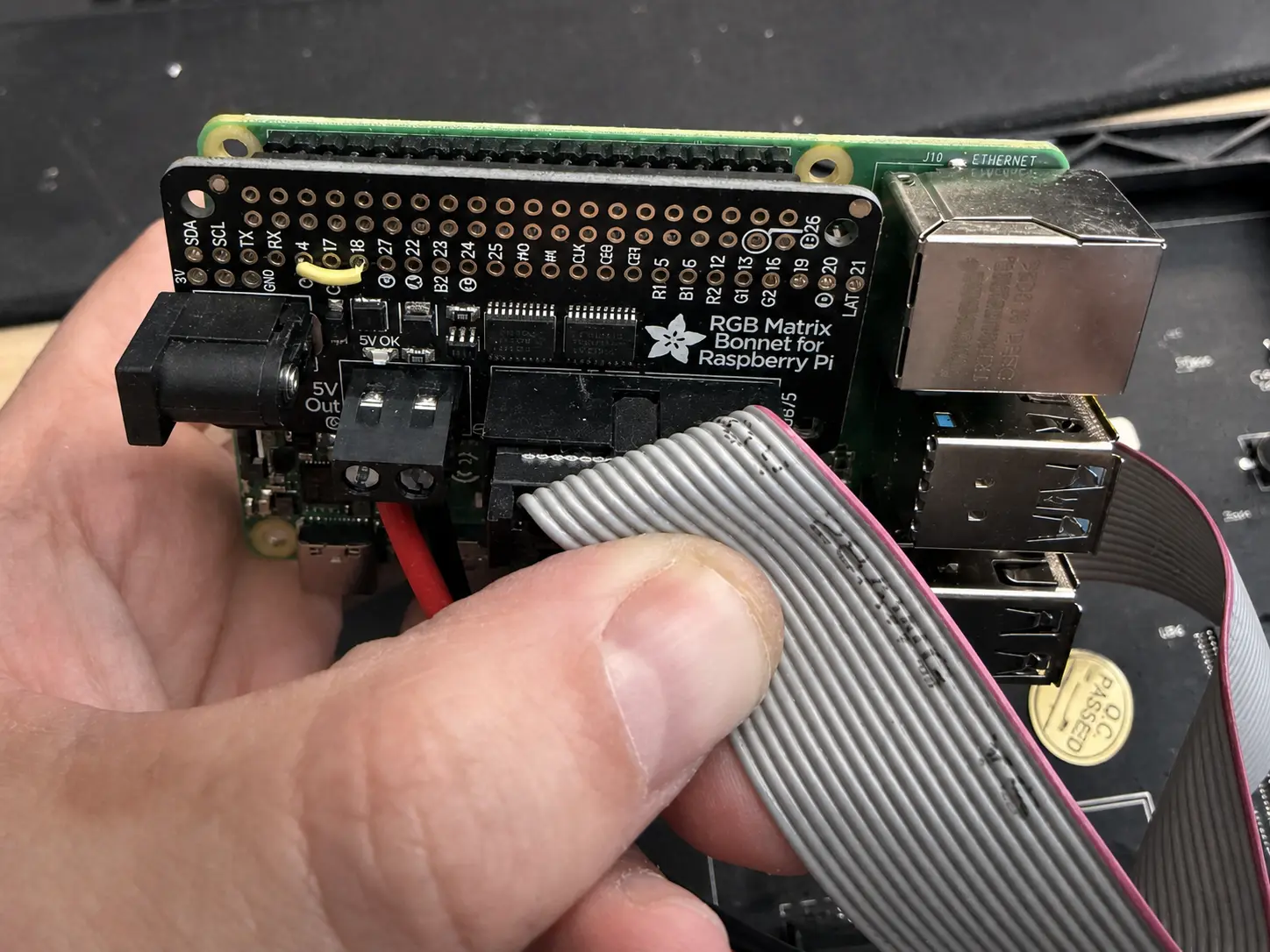A Raspberry Pi fitted with an Adafruit RGB Matrix Bonnet and ribbon cable for the scoreboard.